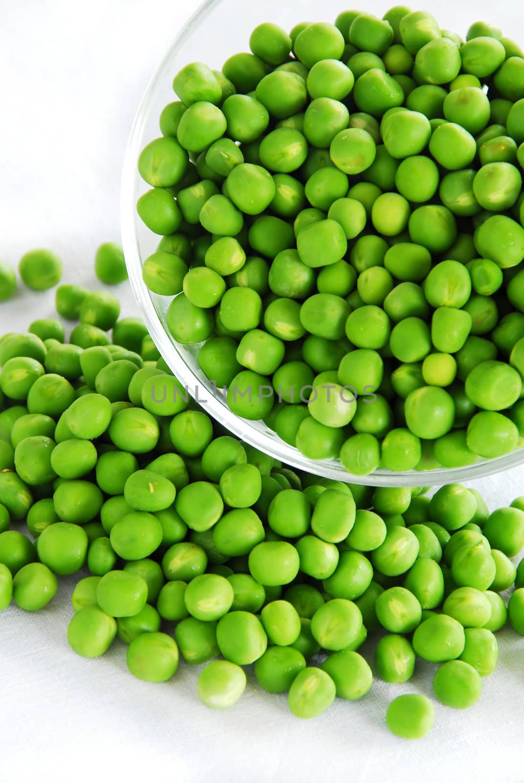 young fresh green spring peas scattered from glass bowl