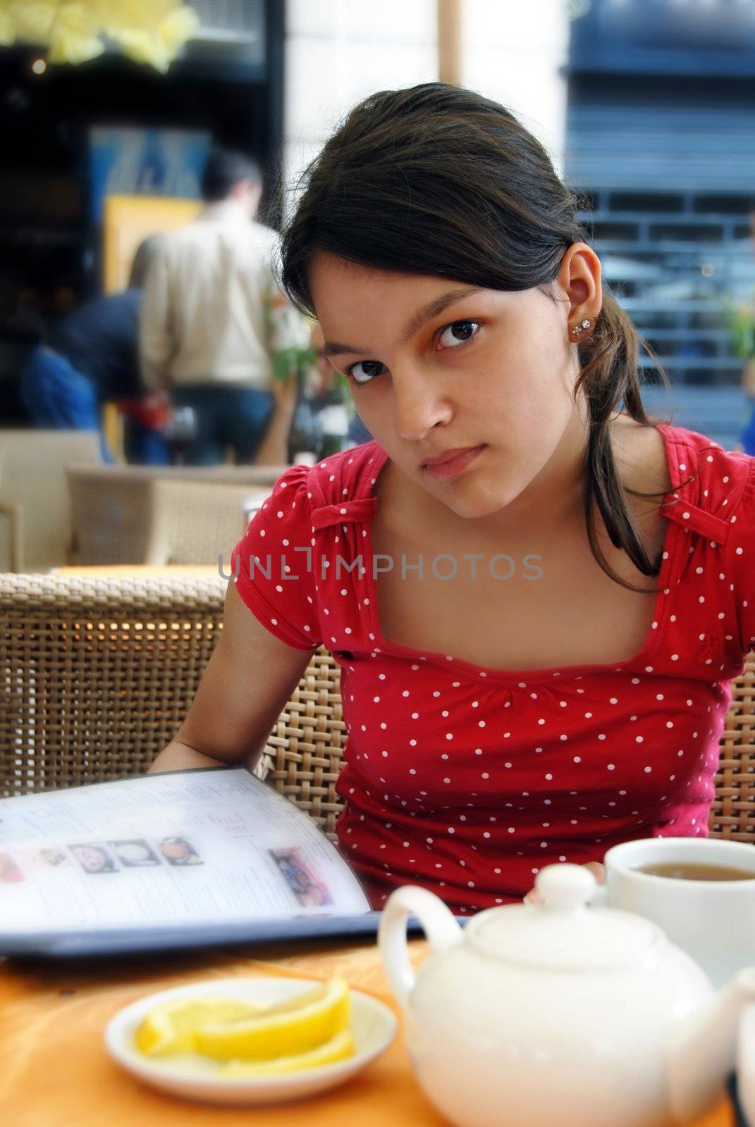 caucasian teenage girl portrait, sitting in street cafe with menu in hands