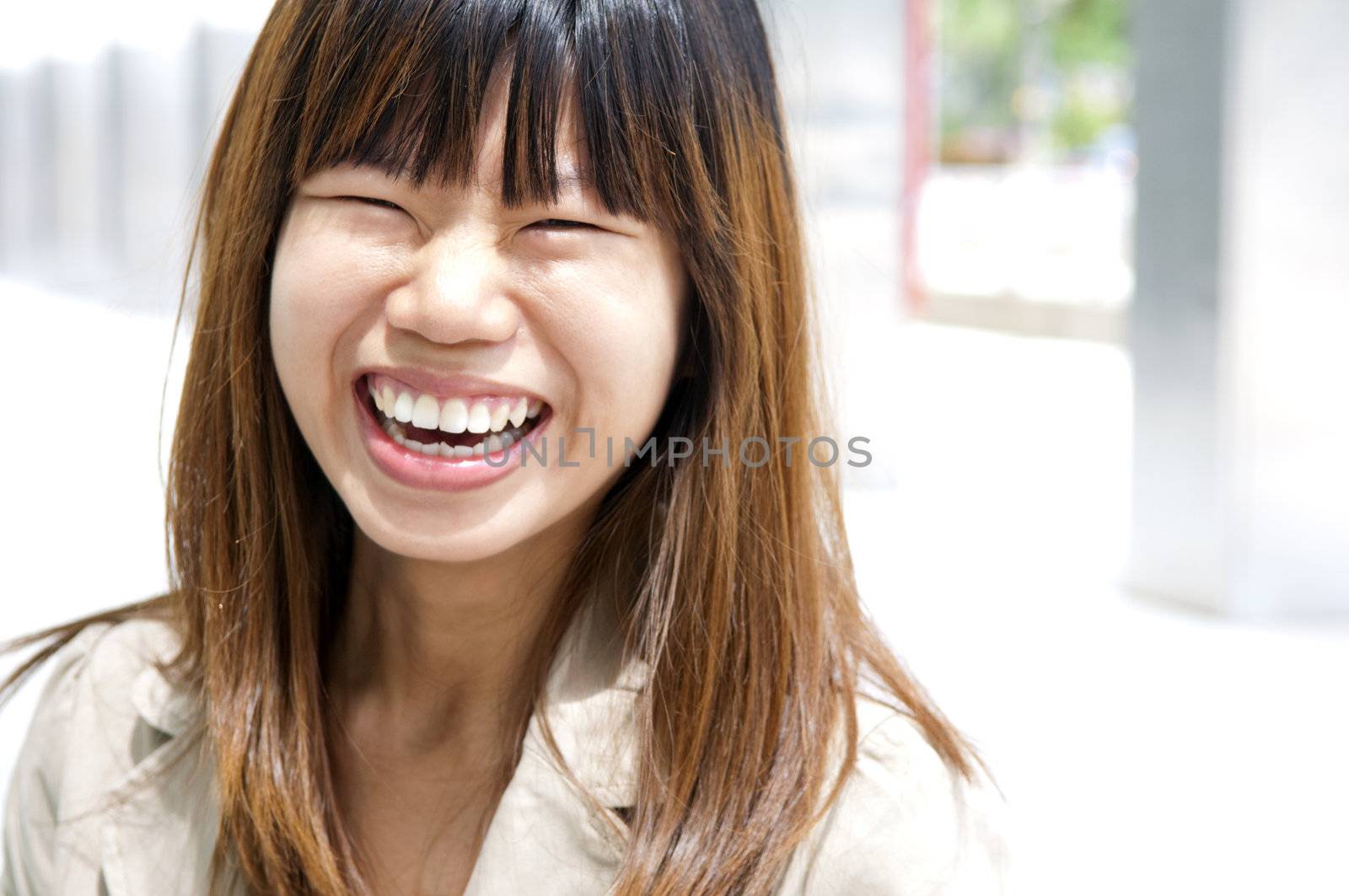 Asian female with her cheerful smile, outside modern building.