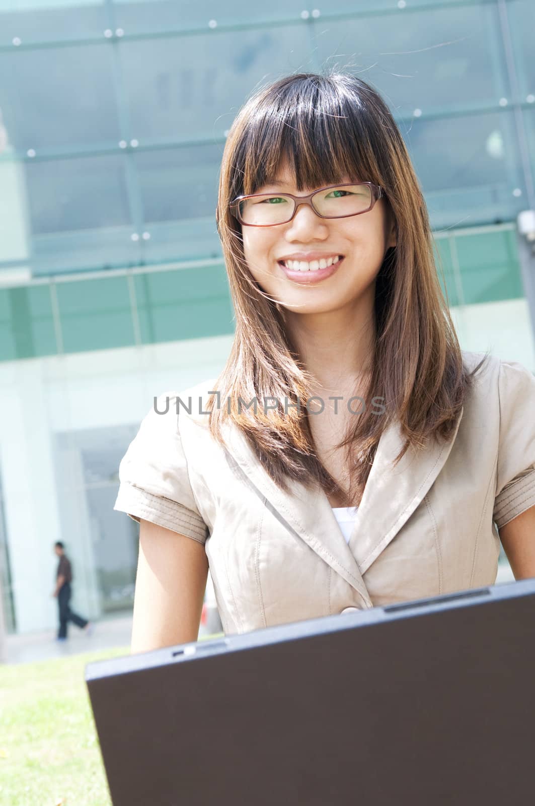 Asian student using laptop outside modern building