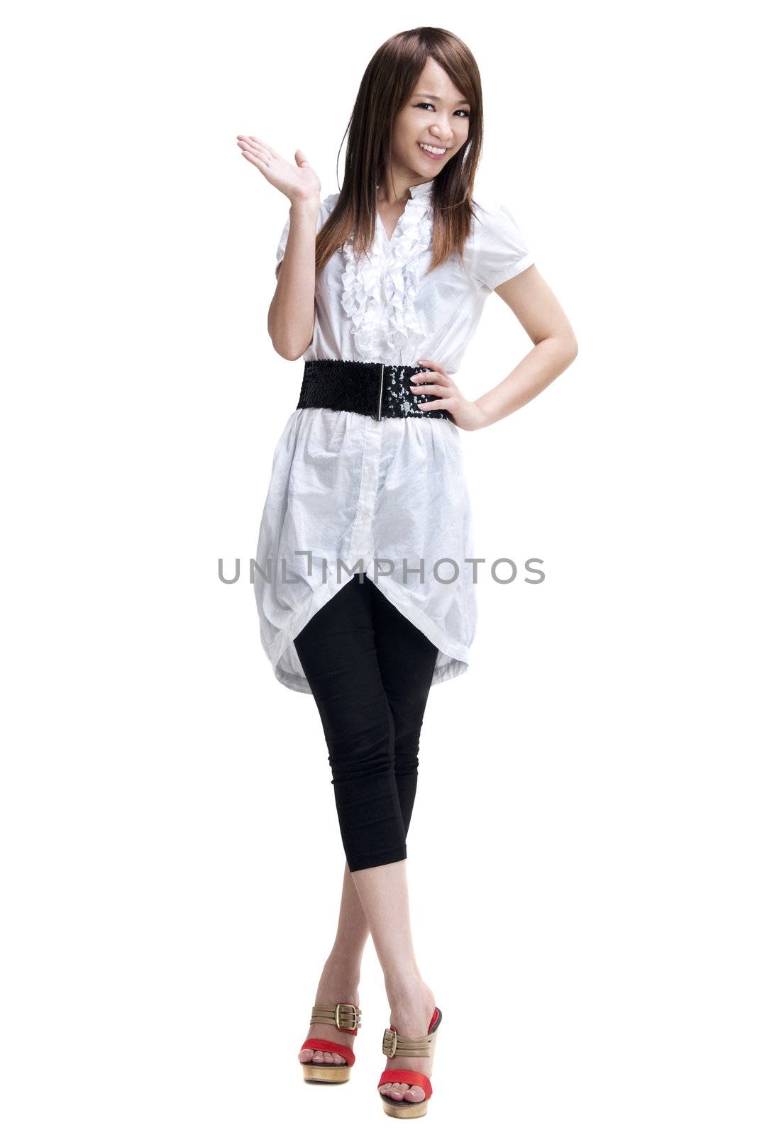 Full length of happy cheerful beautiful Japanese Asian young woman holding her hand out and showing copy space for your product.