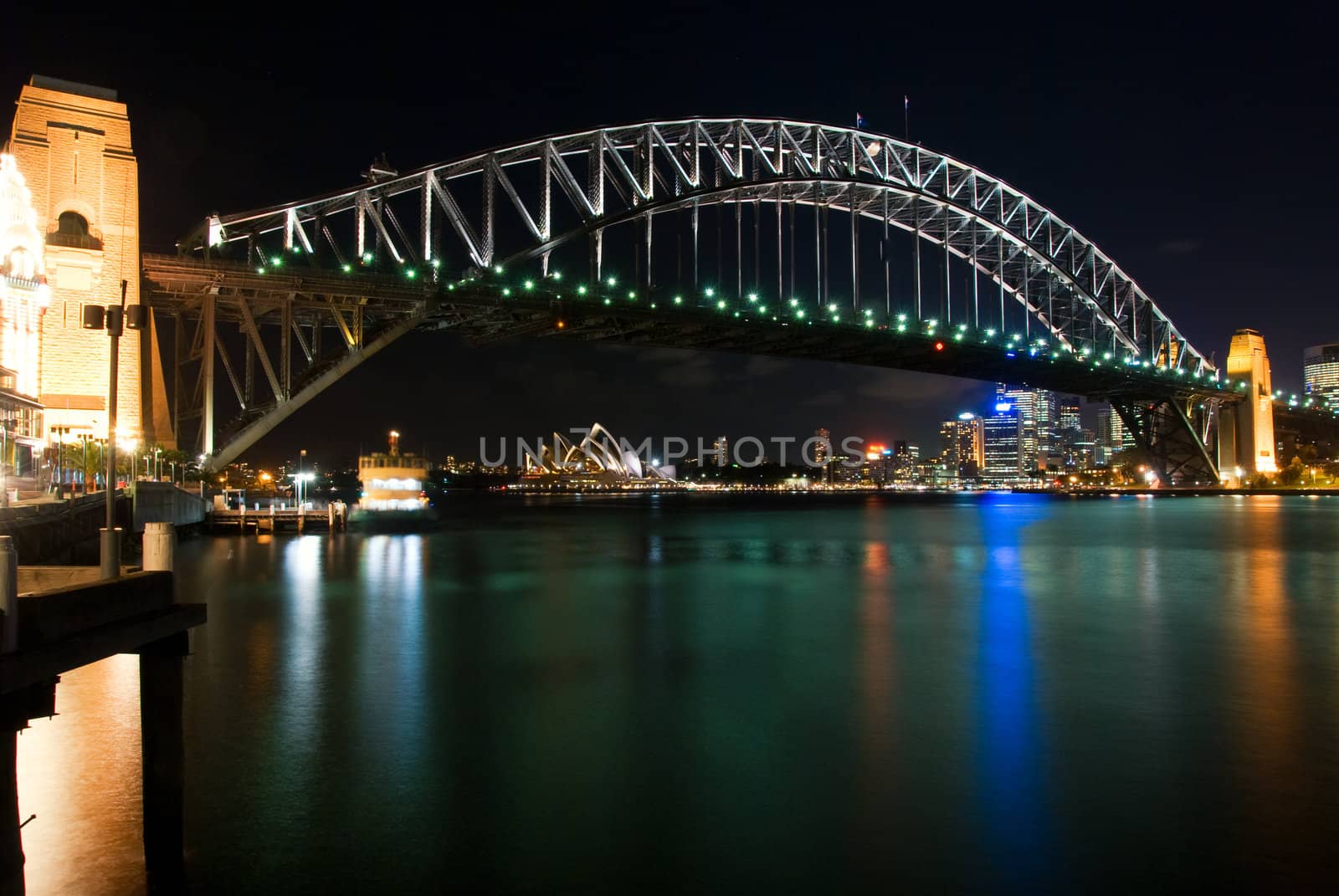 Sydney Harbour Bridge By Night with sparkling water reflection. The Sydney Opera House is at the background.