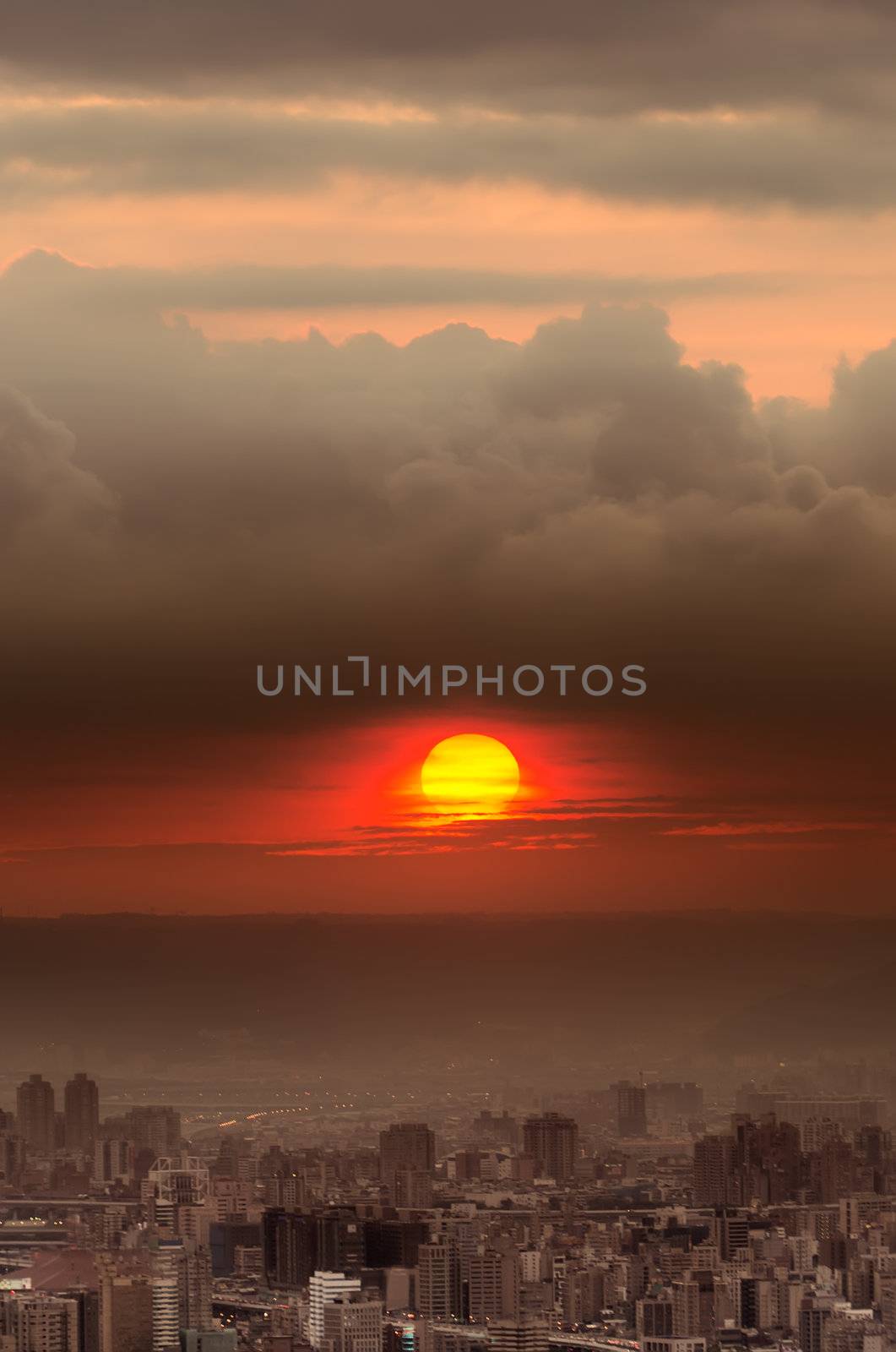 Sunset city scenery with red sun over buildings and clouds in Taipei, Taiwan, Asia.