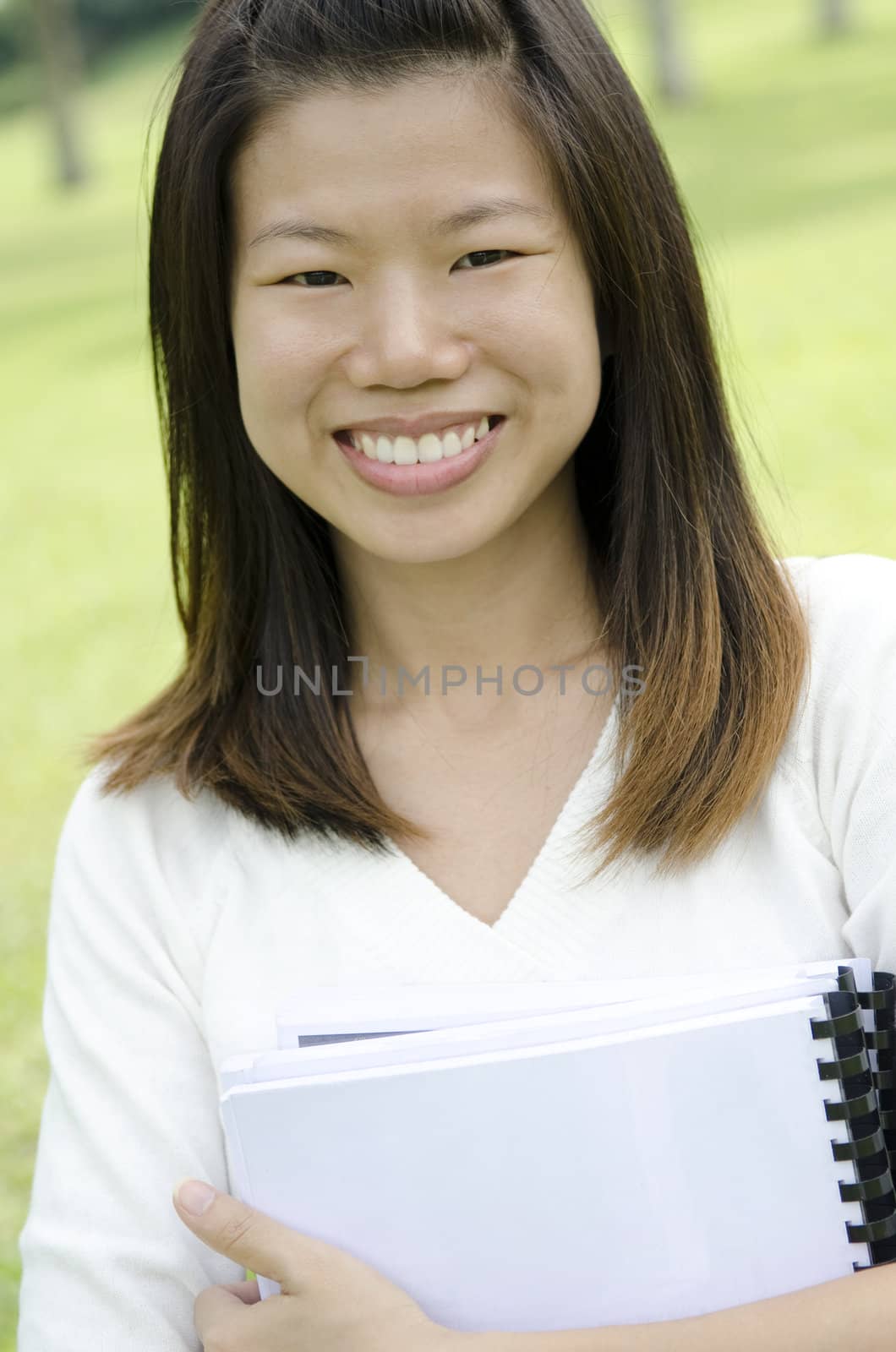Asian college student smiling, standing at outdoor.