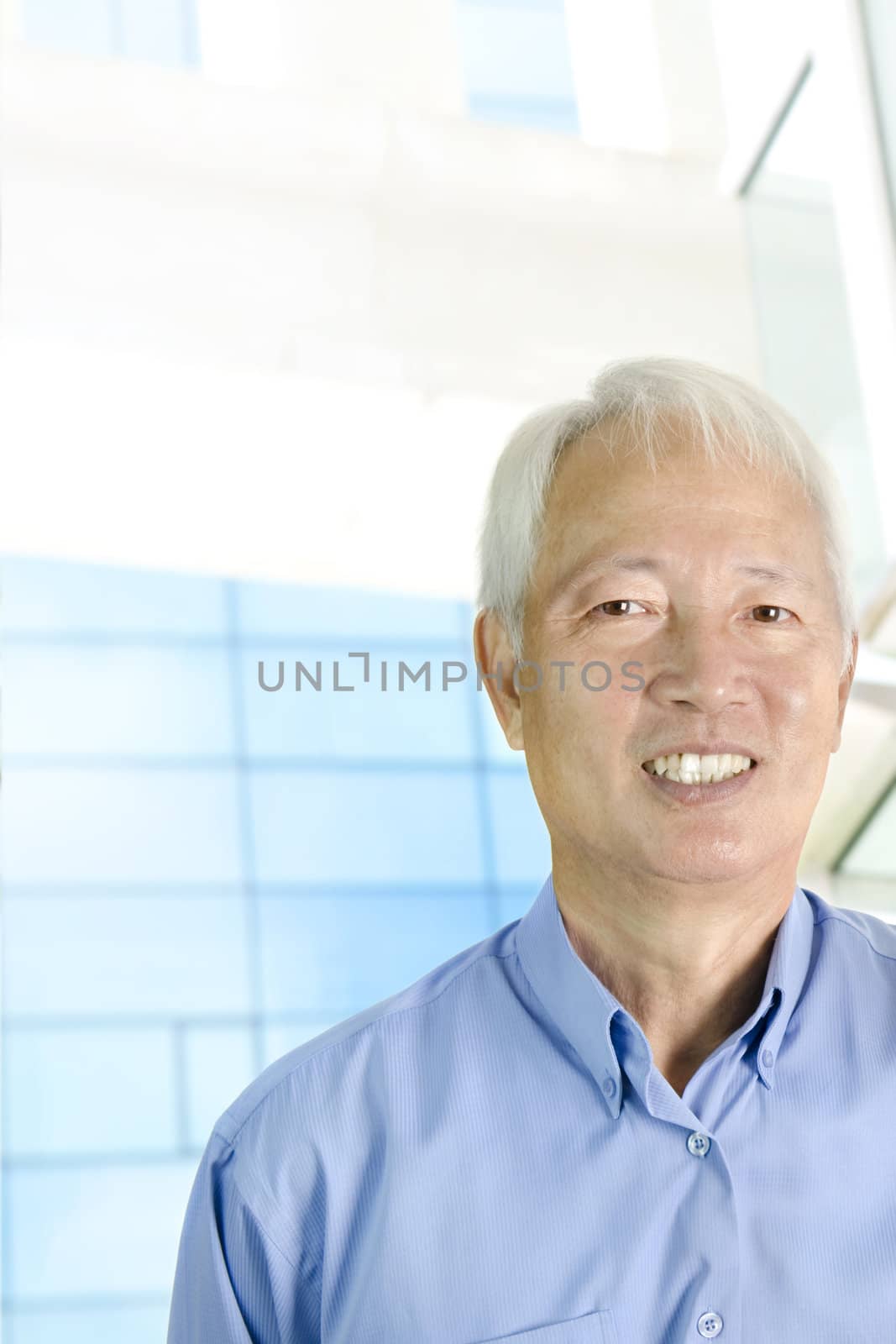 Portrait of an Asian  senior businessman standing in front modern building