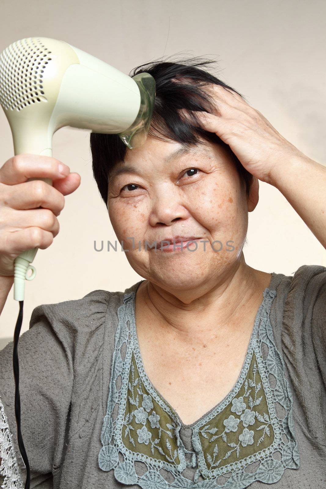 asia female drying her hairs with drier