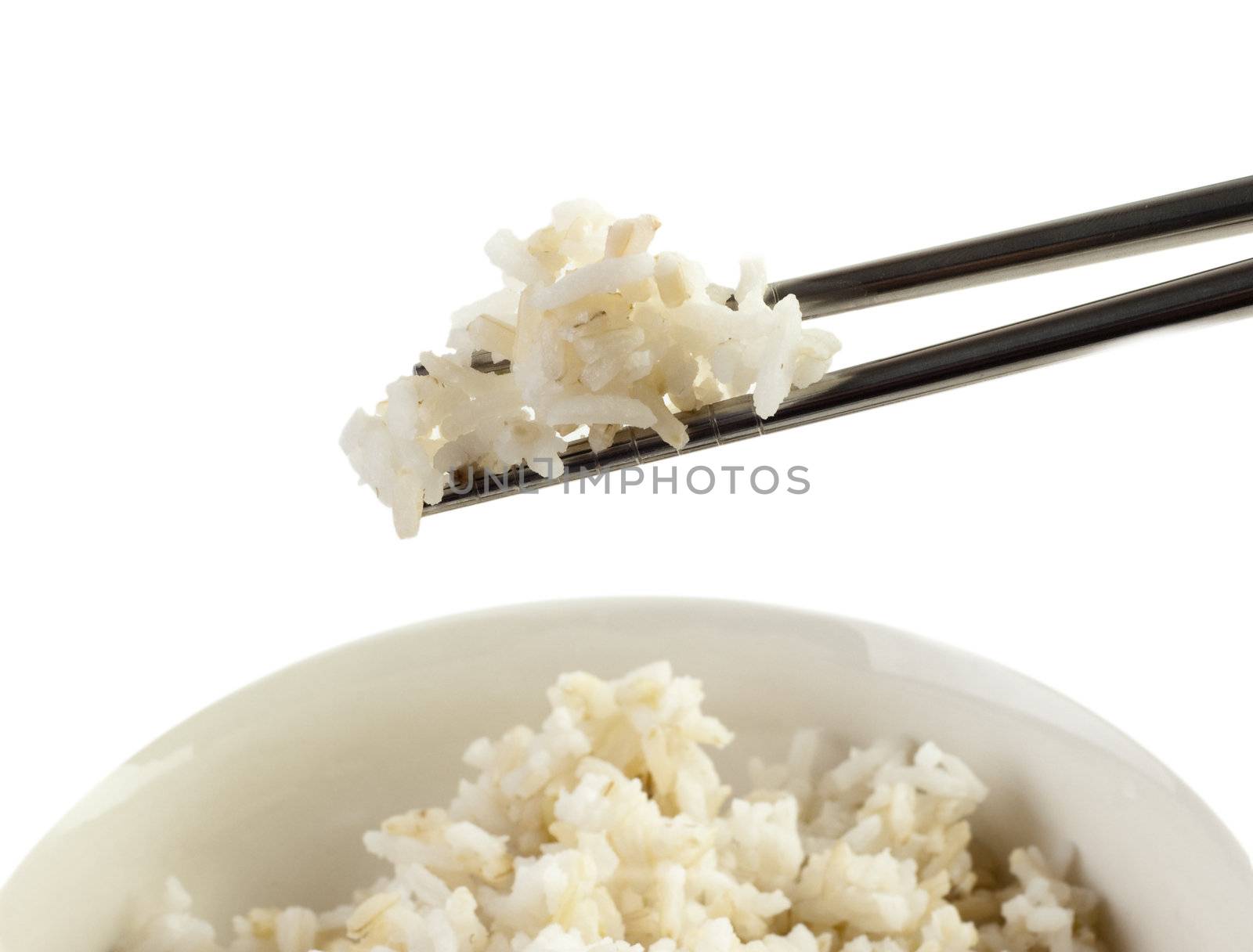 A bowl of cooked brown rice, in an Asian style bowl, with chopsticks isolated on white.