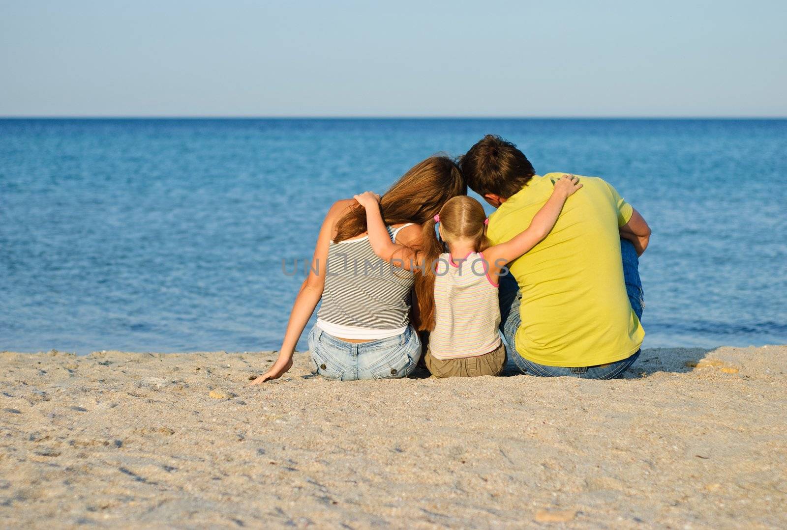 Father, mother and daughter sitting on the beach