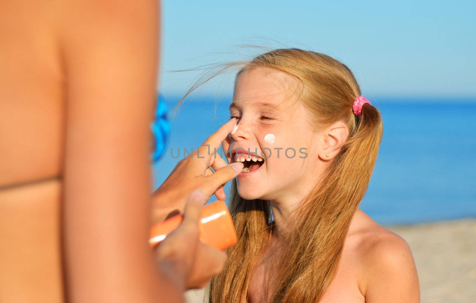 Mother smearing her daughter with sunblock