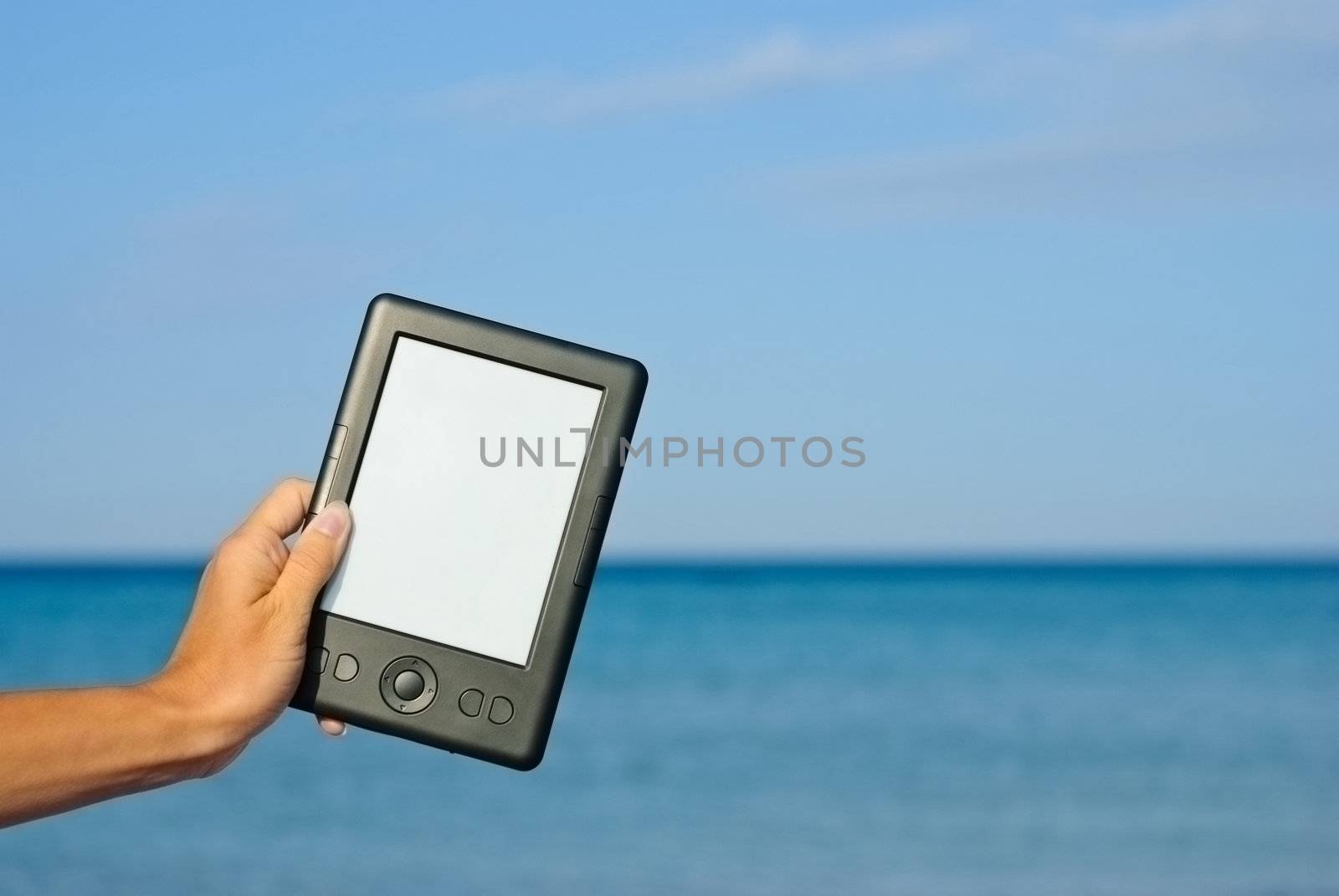 Female hand holding an e-book against the sea