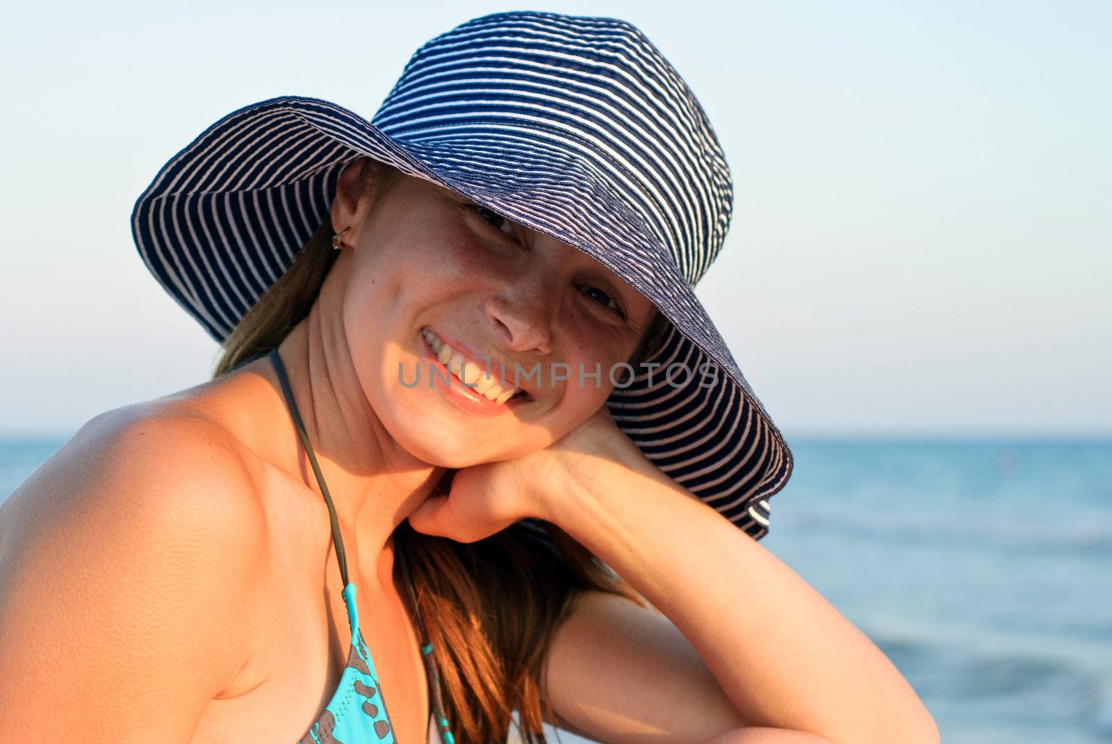 Young woman in a hat sitting on a beach