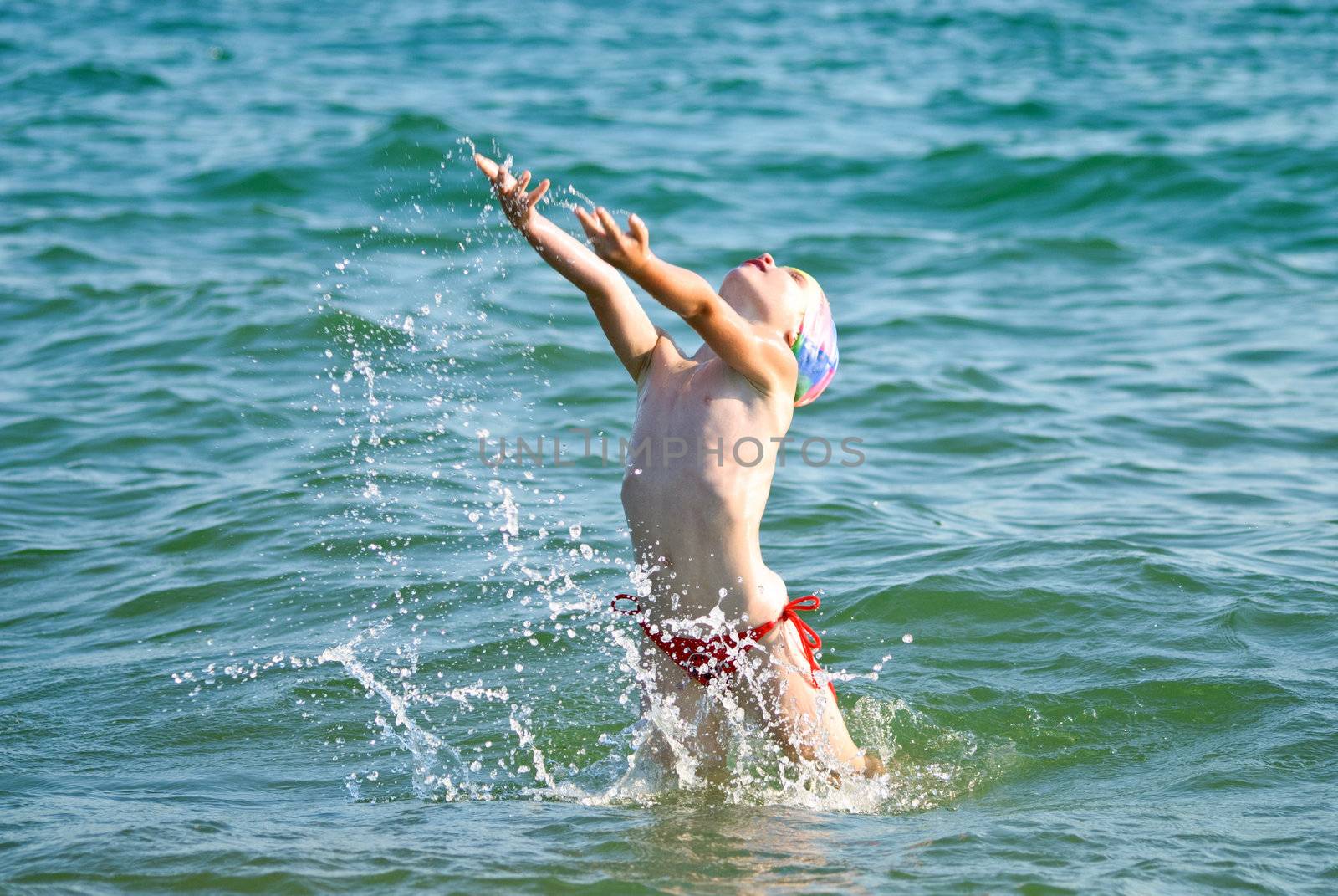 Little girl bouncing up from the sea