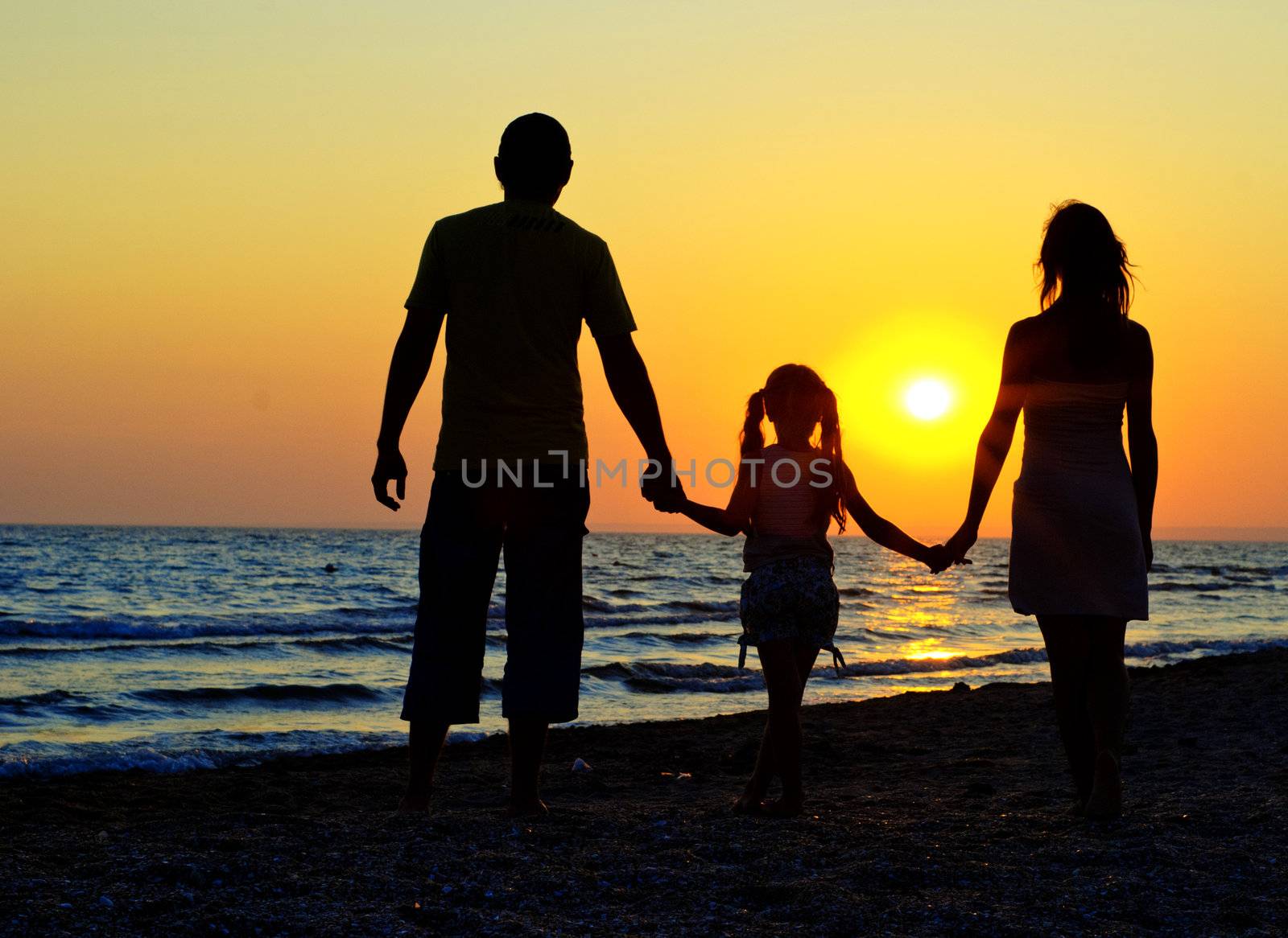 Father, mother and daughter walking on the beach