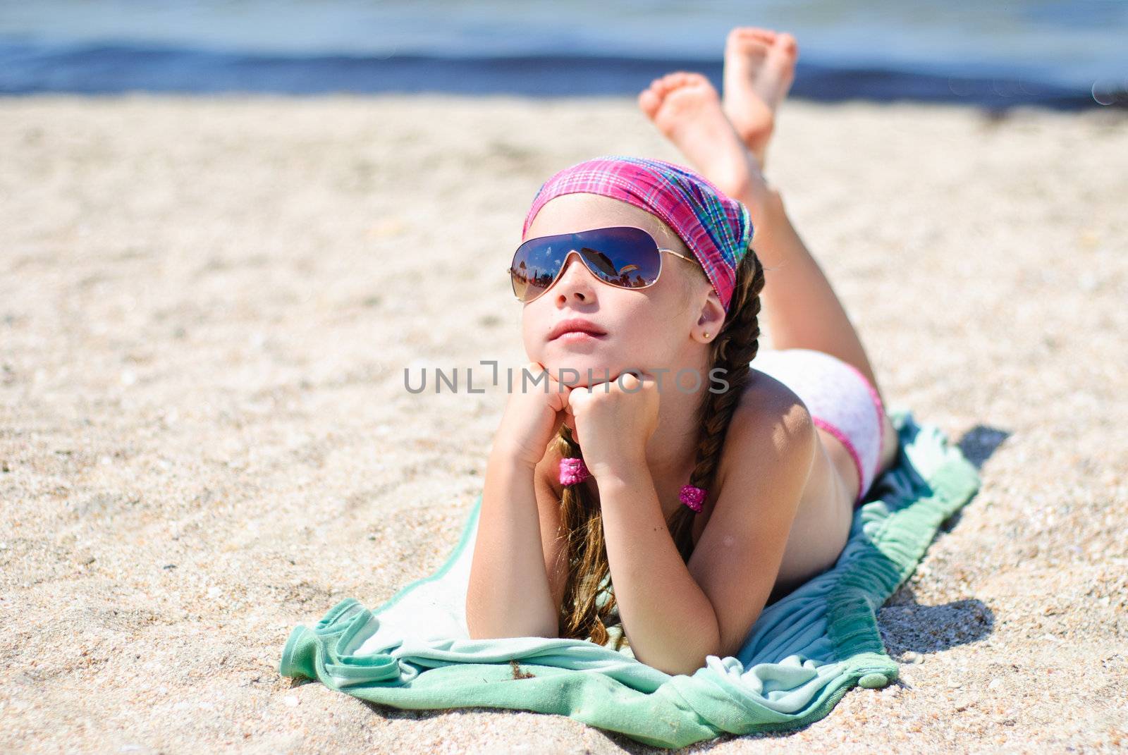 Happy little girl in sunglasses on the beach