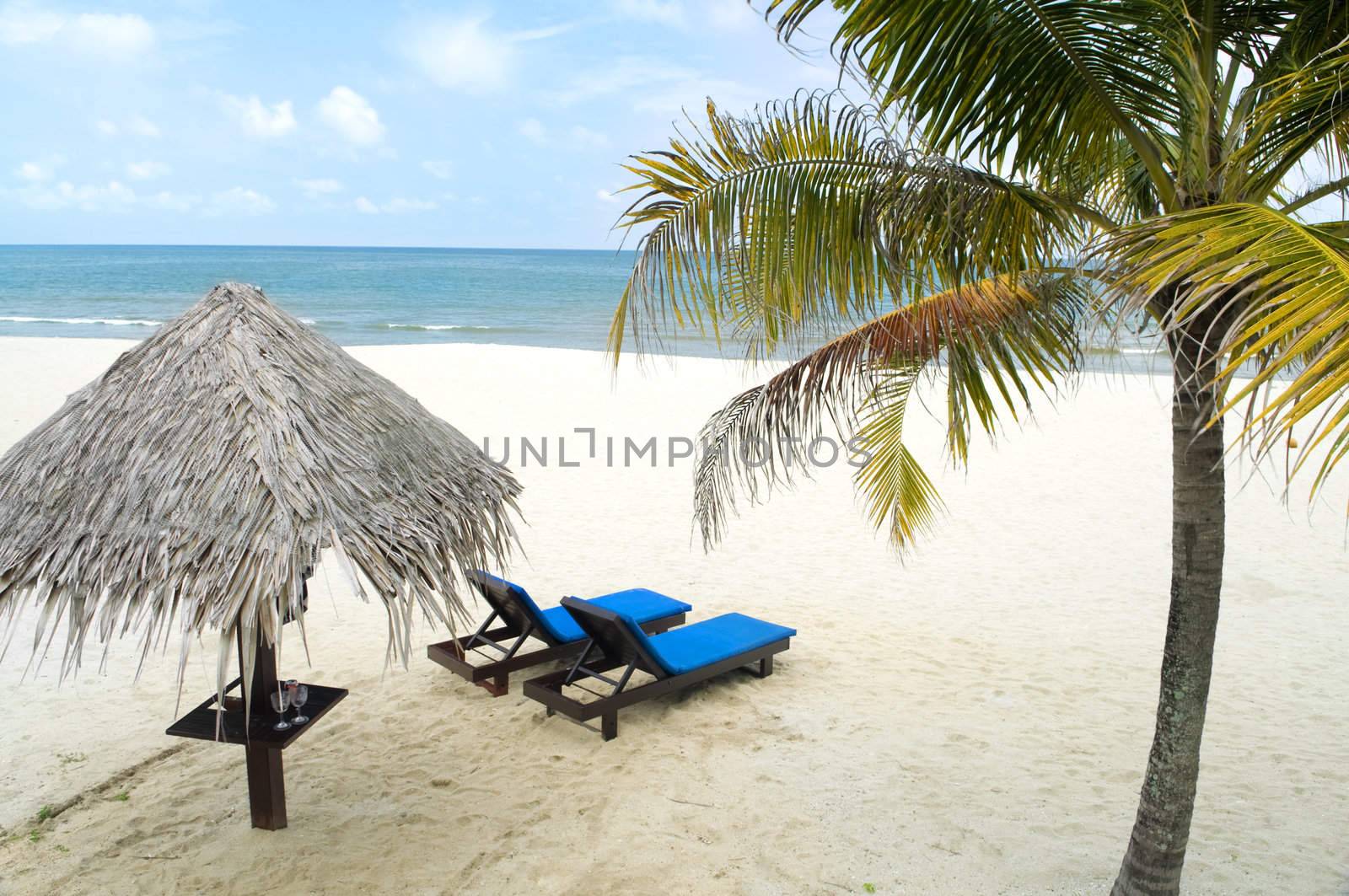 Tropical beach with hut and chairs 
