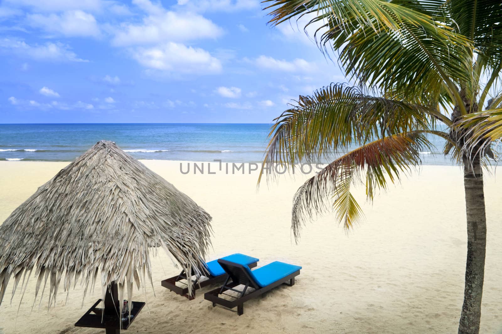 Tropical beach with hut and chairs.
