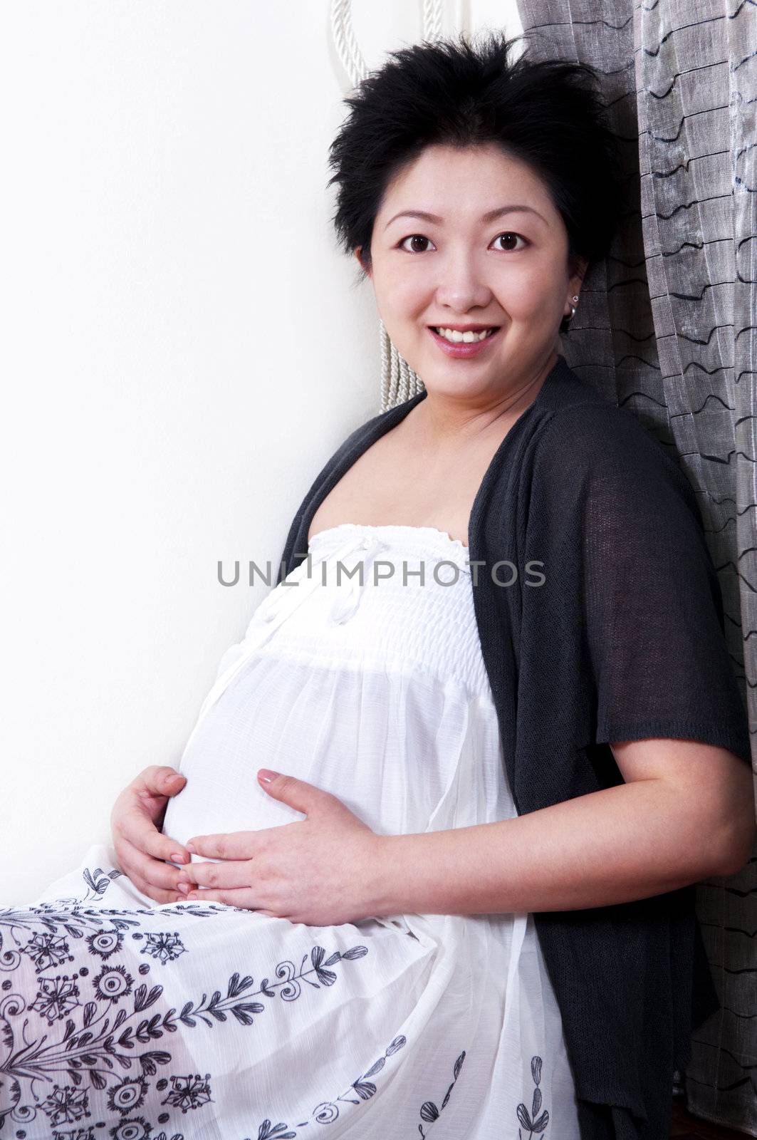 Asian Pregnant woman holding hand on stomach.