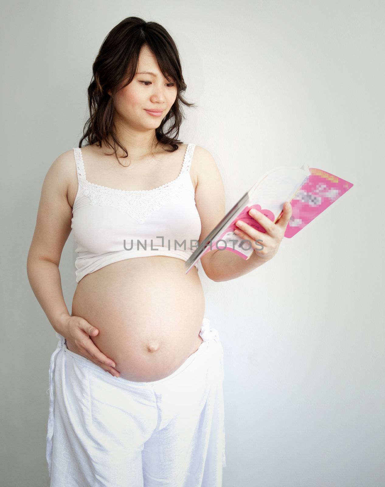 8 months pregnant Asian women reading book.
