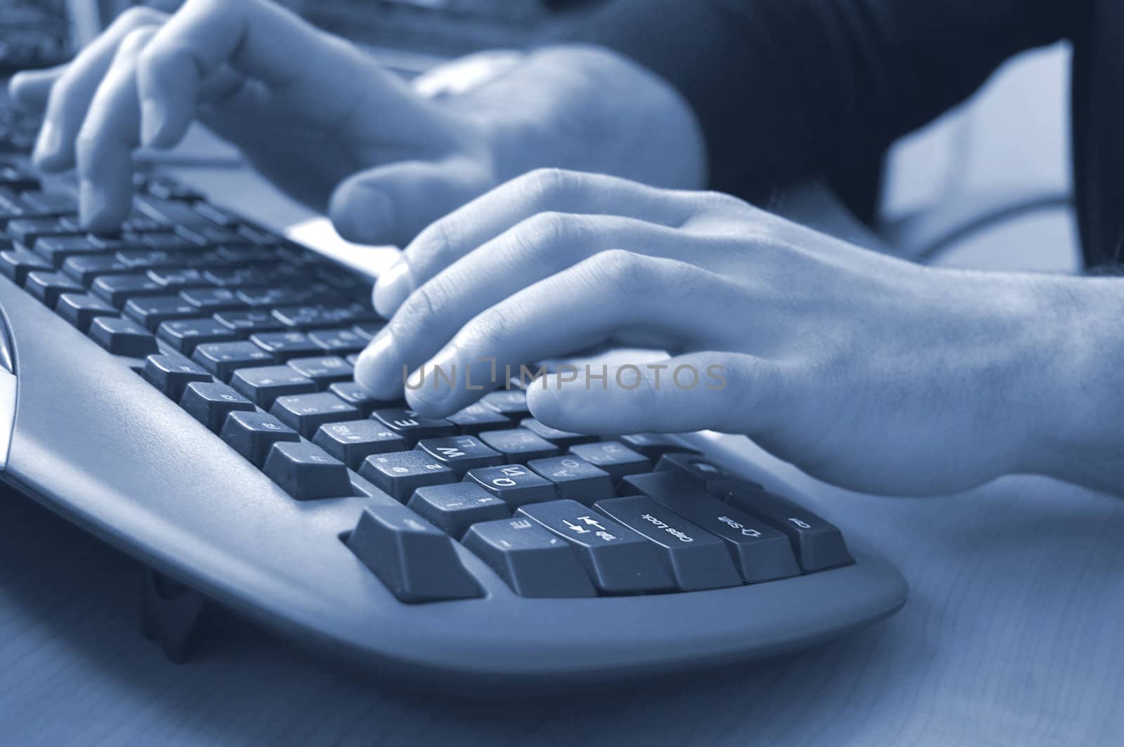 male hand typing on black keyboard, blue toned
