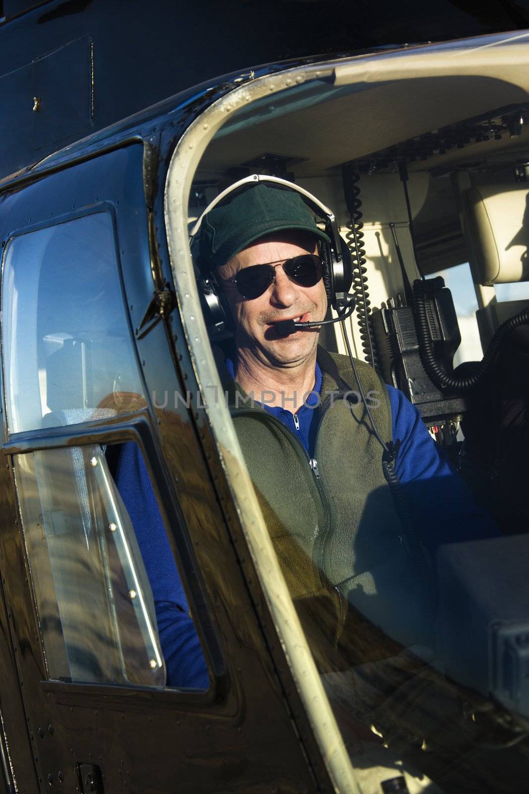 Portrait of helicopter pilot sitting in cockpit looking at viewer.
