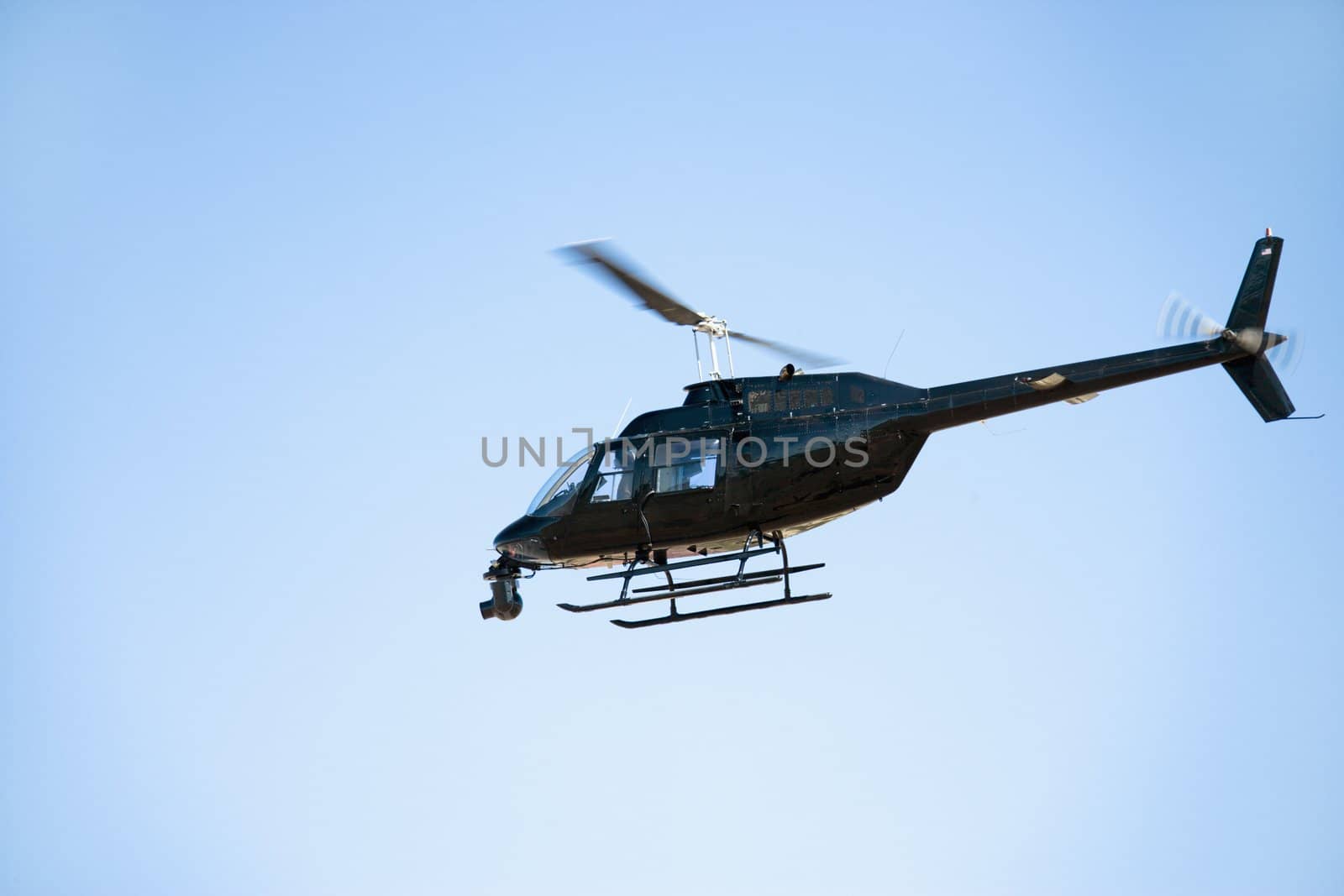 Low angle shot of helicopter flying through blue sky.