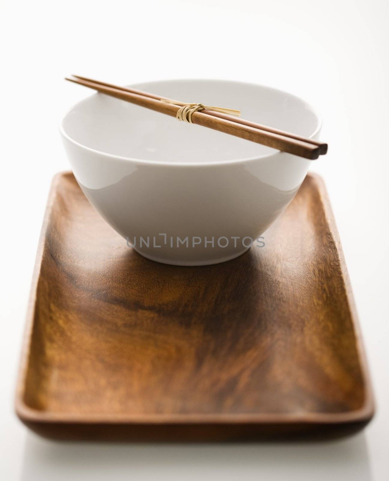 Asian bowl with chopsticks on wooden tray.