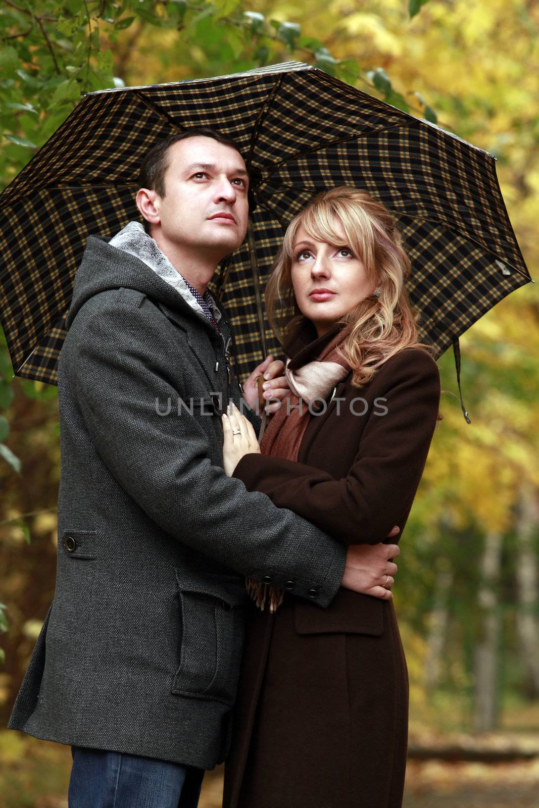 Couple in autumn park under a umbrella