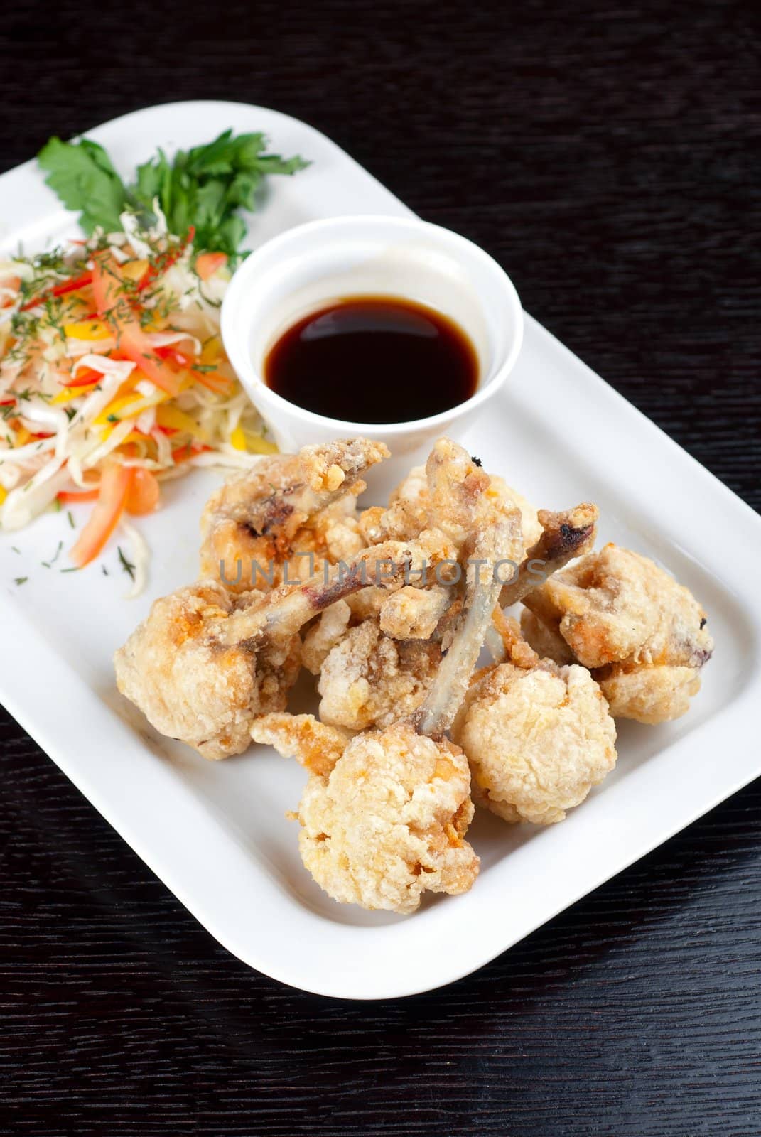 Fried chicken wings garnished with fresh vegetables with Teriyaki sauce