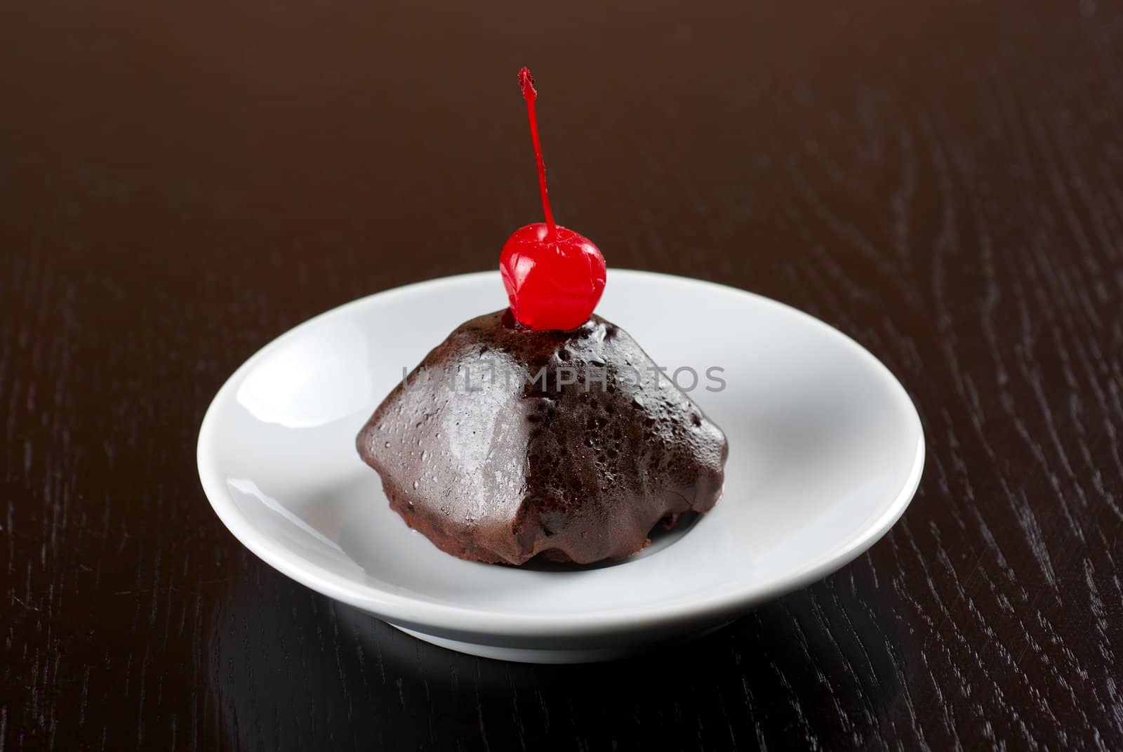 fresh baked chocolate cupcake with cherry on a wooden table