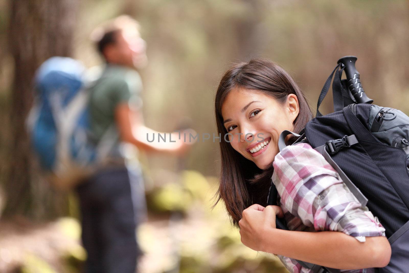 Hiking. Woman hiker smiling in forest with male hiker in the background. Mixed-race Asian Caucasian female model happy. From Aguamansa, Tenerife, Spain