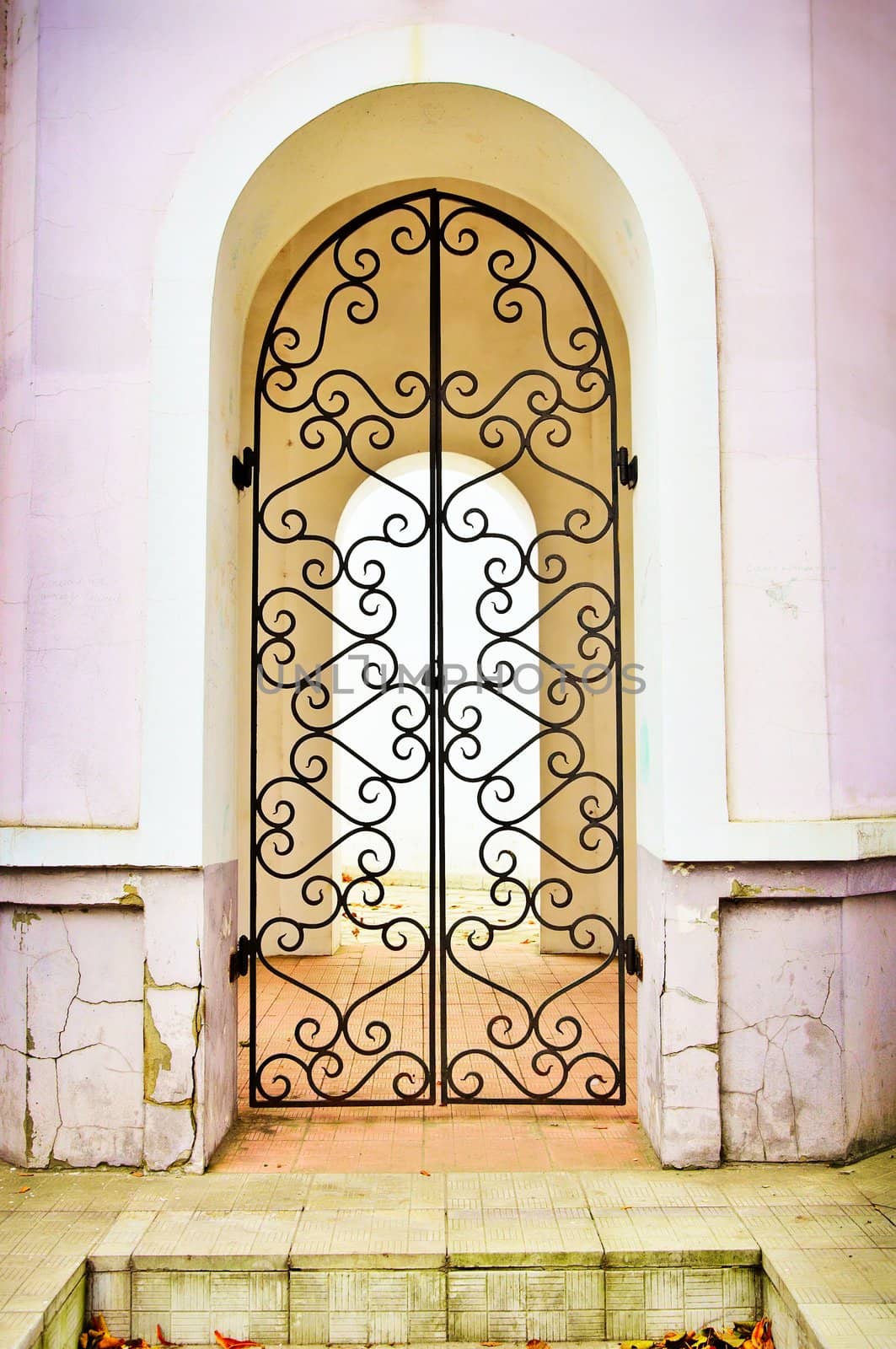 Facade an arch with the closed curly metal door. Isolated