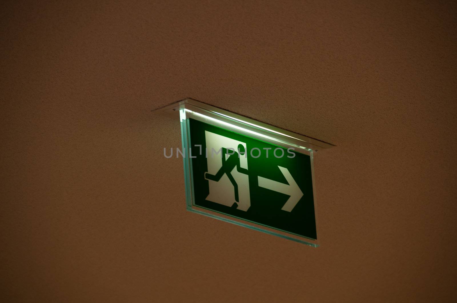 green emergency exit sign showing the way to escape