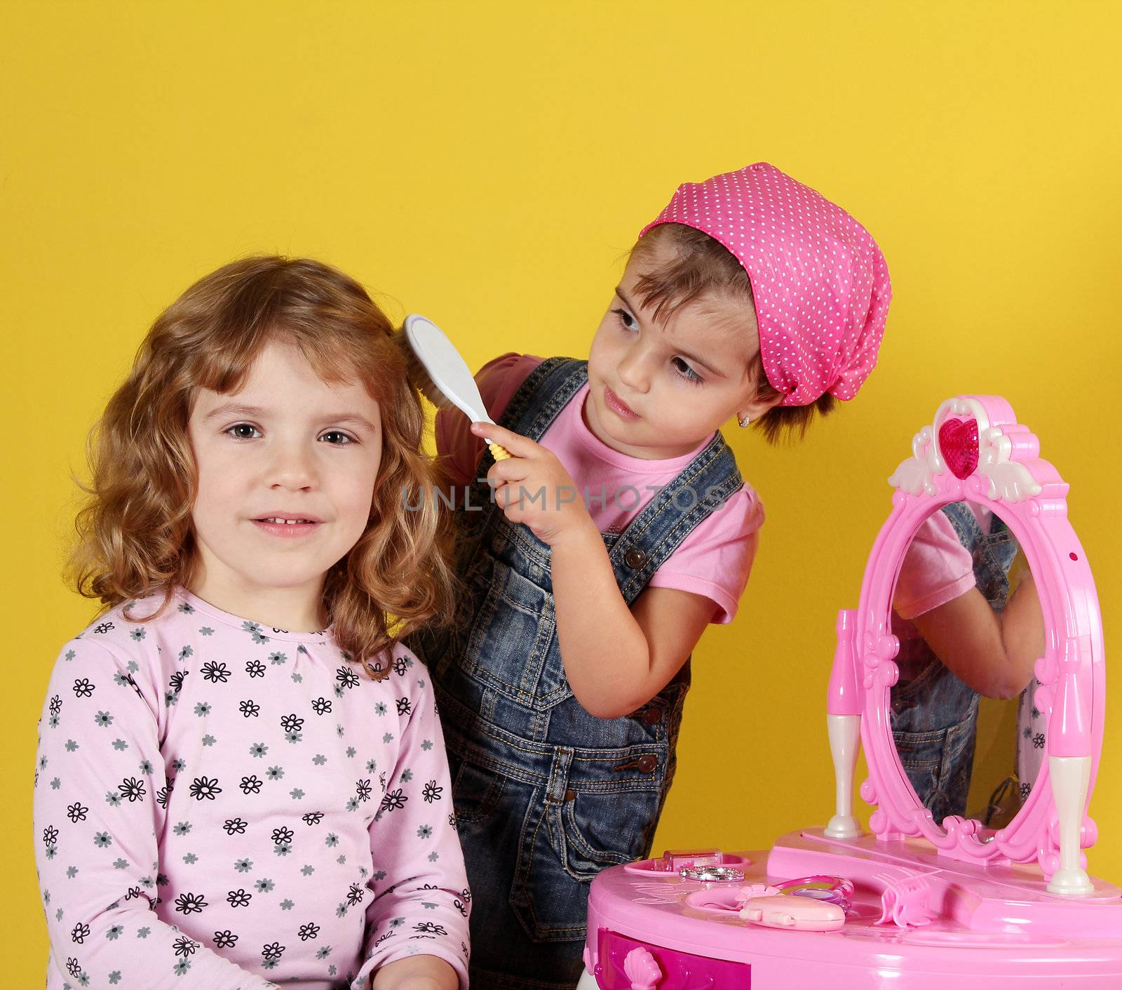 two little girls playing hairdressers by goce