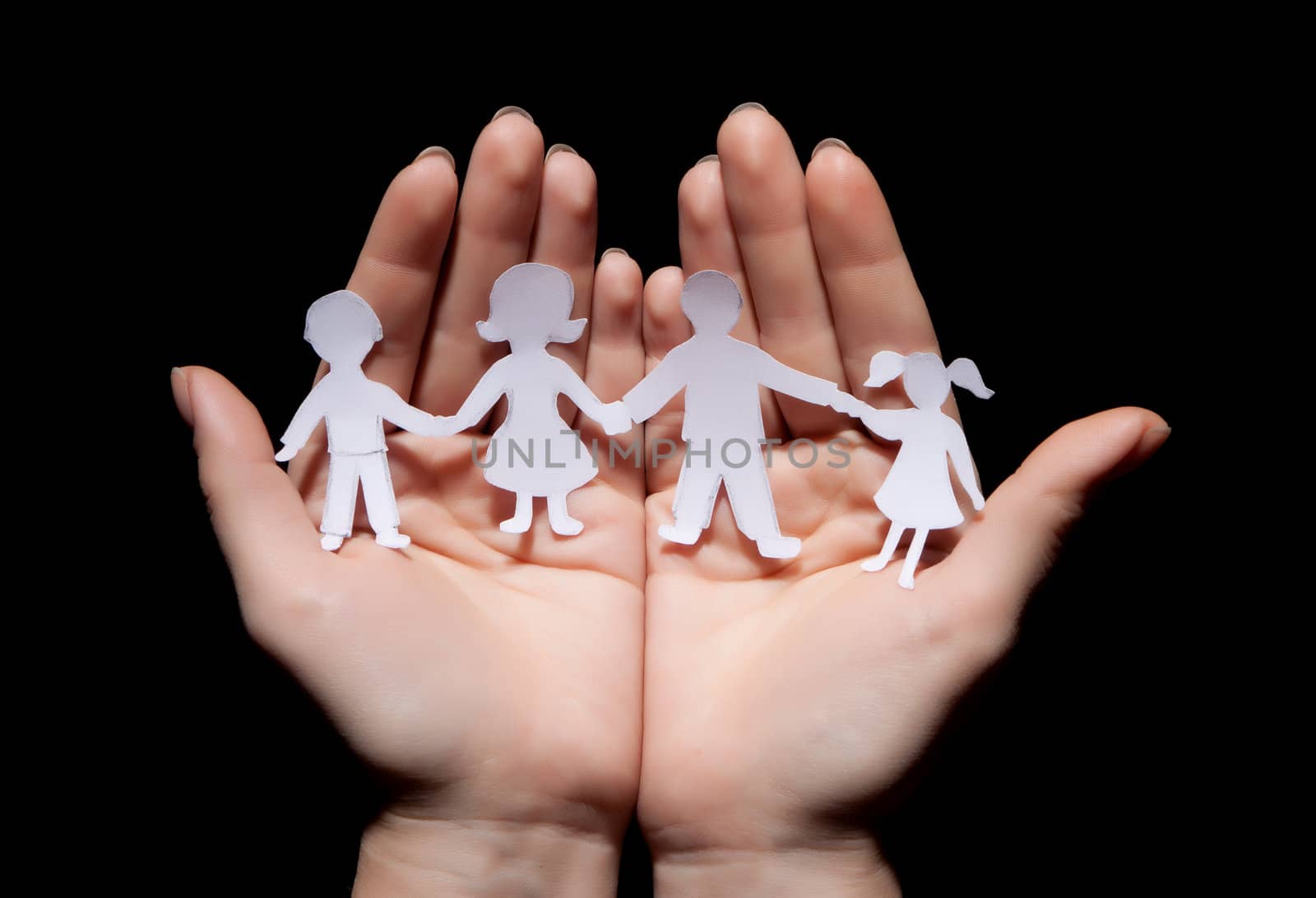 Paper chain family protected in cupped hands on black background