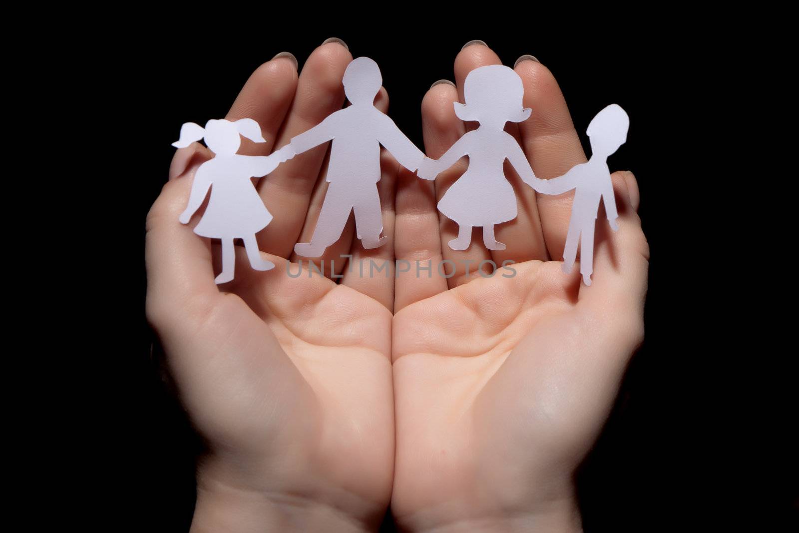 Paper chain family protected in cupped hands on black background