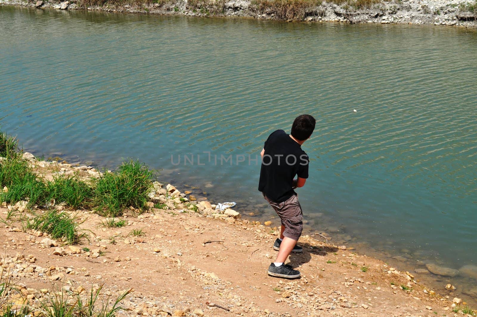 Teen skips rocks over river by RefocusPhoto