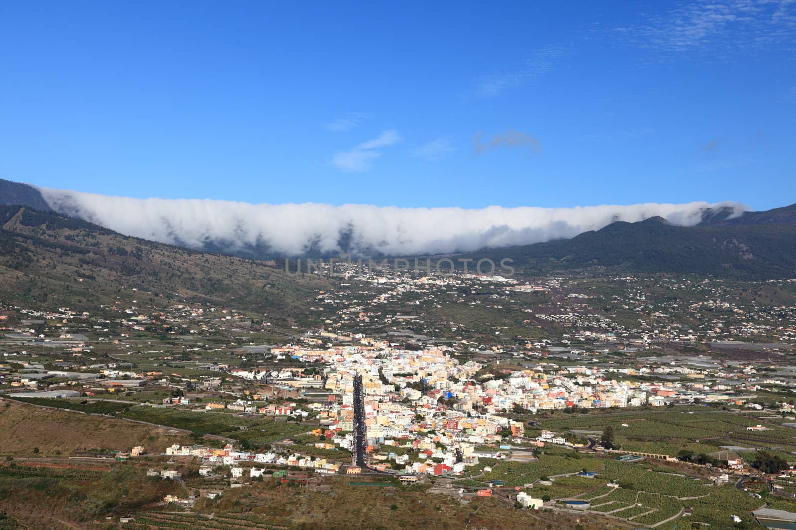 La Palma, Canary Islands. Photo shows the rare and famous cloud phenomena where clouds are falling down over the mountain ridge Cumbre Nueva like a waterfall. Also showing city Los Llanos de Aridane