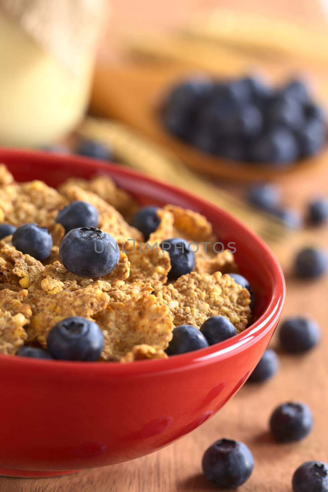 Wholewheat flakes with fresh blueberries with a glass of yogurt and blueberries in the back (Selective Focus, Focus on the blueberry in the middle of the bowl) 