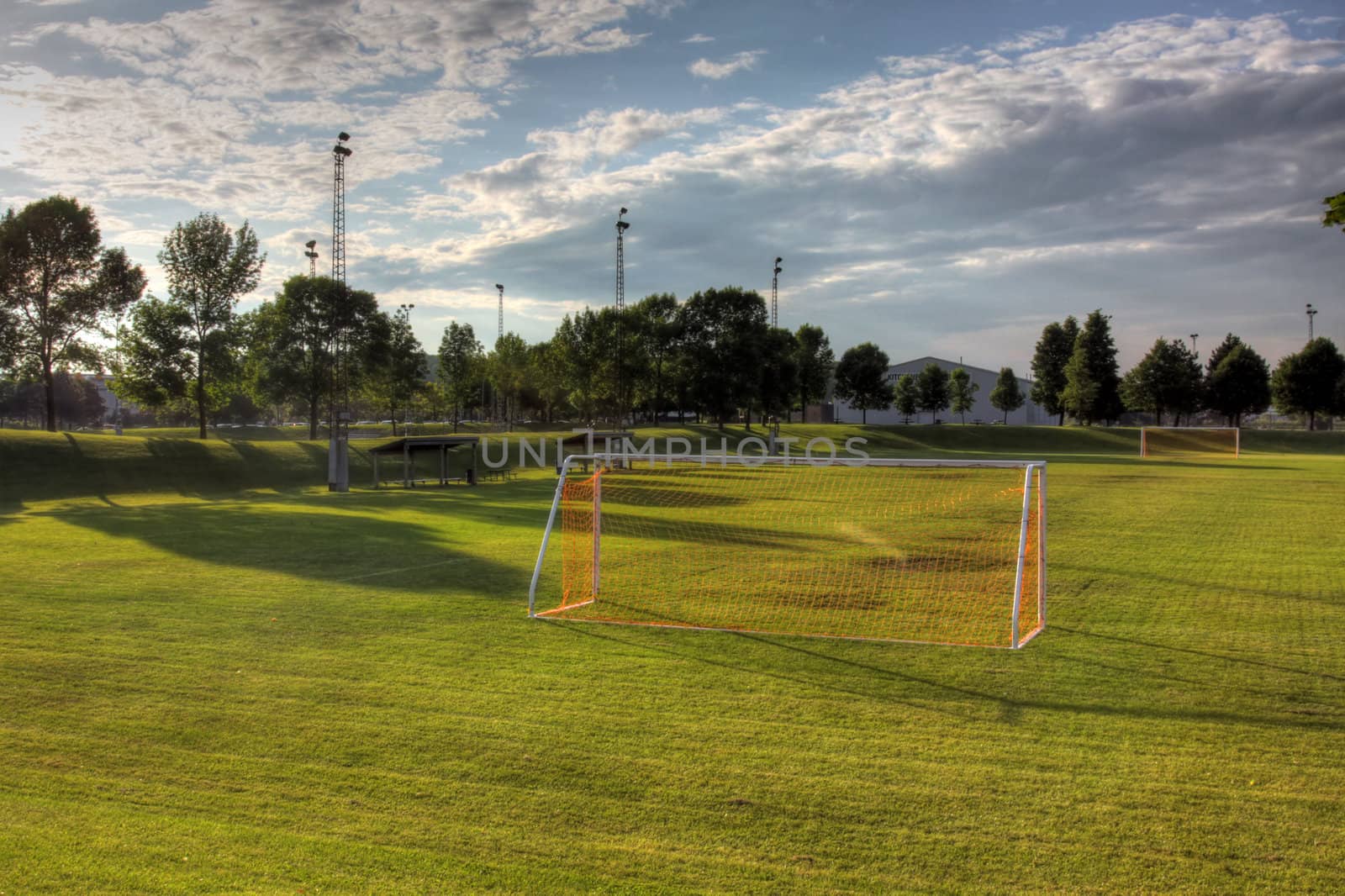A mixed sky over an unoccupied soccer field with trees in the background. (HDR photo)
