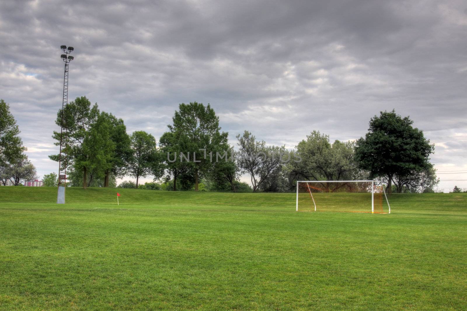 A cloudy unoccupied soccer field with trees in the background. (HDR photograph)