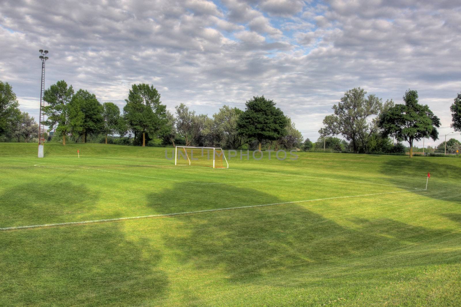 A cloudy unoccupied soccer field with trees in the background. (HDR photograph)

