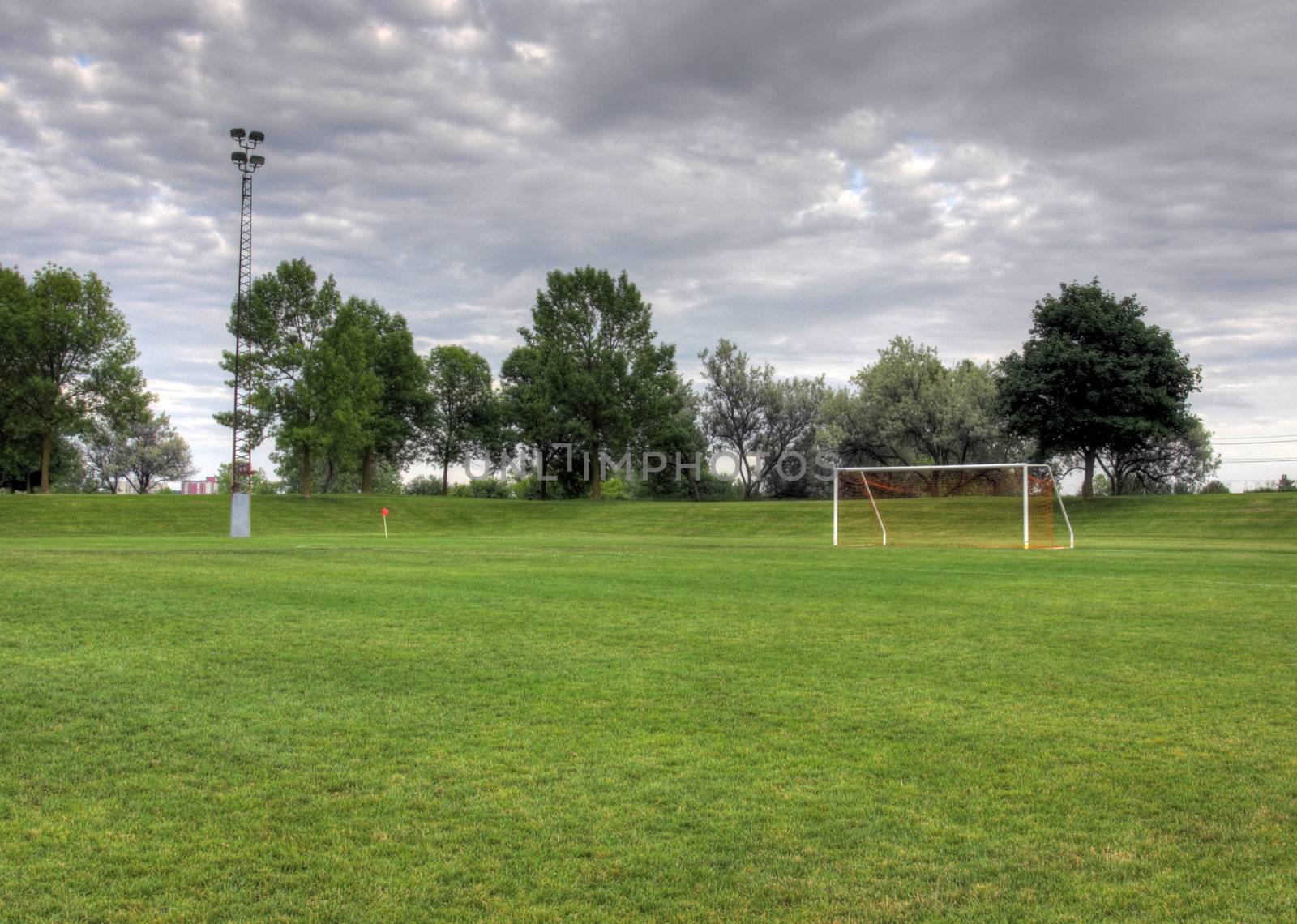 A cloudy unoccupied soccer field with trees in the background. (HDR photograph)
