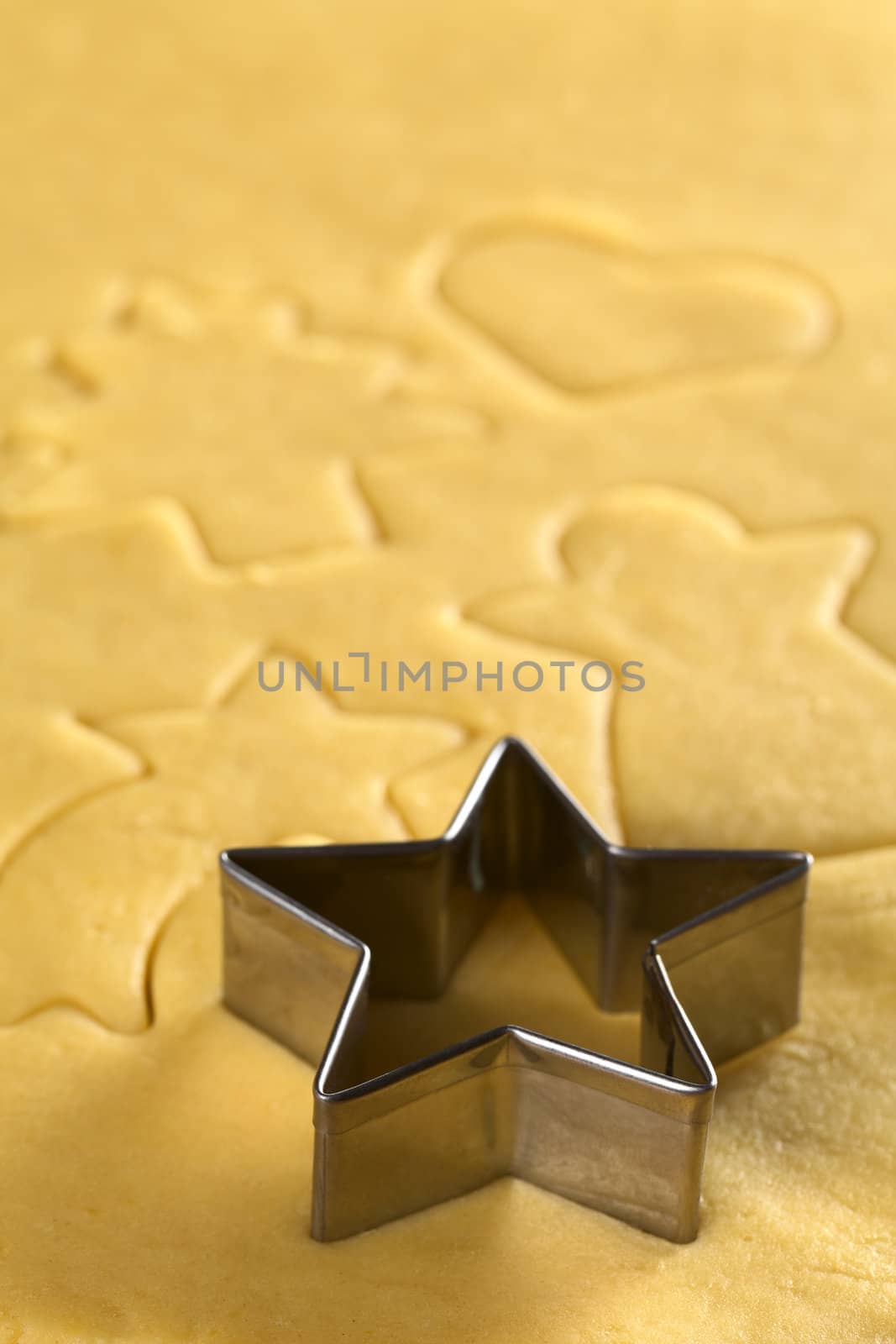 Star-shaped cookie cutter and other Christmas shapes cut into dough (Selective Focus, Focus on the two front edges of the star-shaped cutter)