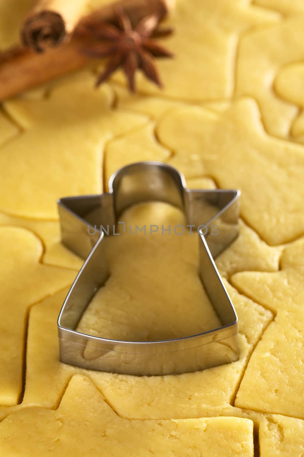 Cutting out Christmas cookies from shortcrust dough with an angel shaped cutter (Selective Focus, Focus on the lower edge of the cutter) 