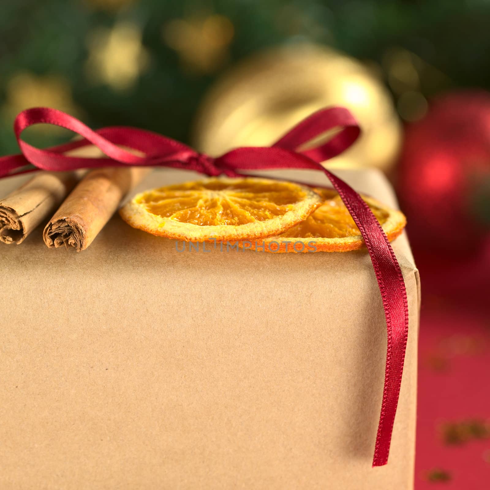 Christmas present decorated with dried orange slices and cinnamon (Selective Focus, Focus on the front of the orange slices and the cinnamon stick)