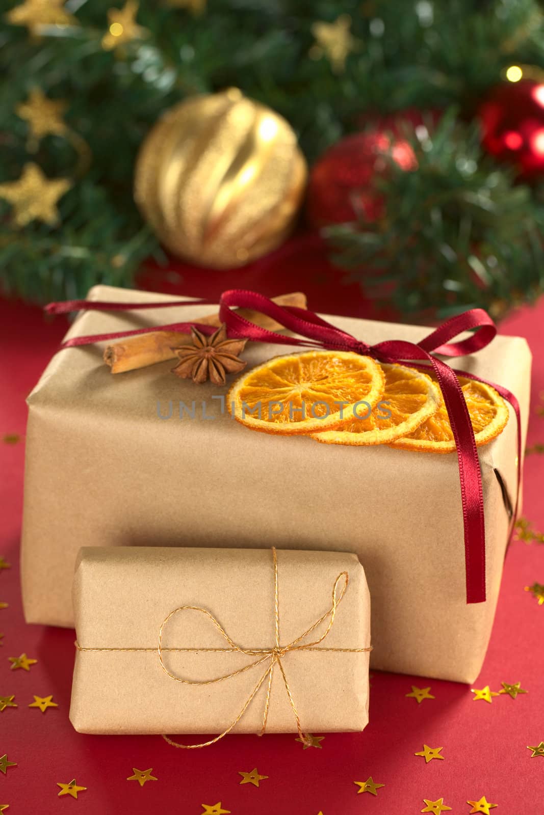 Christmas presents decorated with dried orange slices, cinnamon and anise (Selective Focus, Focus on the front of the orange slices and the ribbon on the small present)