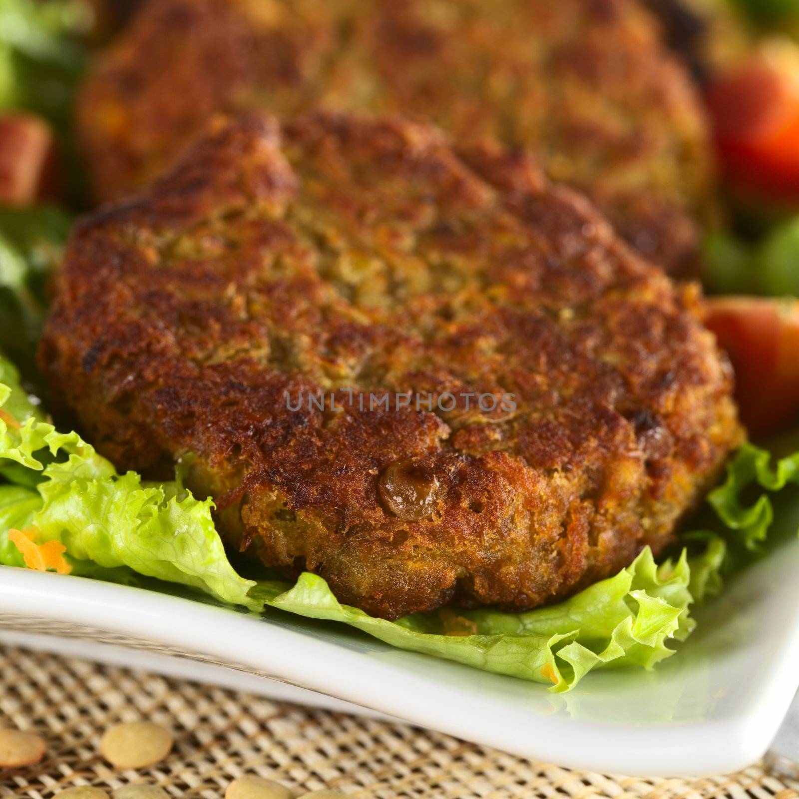 Vegetarian lentil burger made of brown lentils and grated carrots served on lettuce (Selective Focus, Focus on the front of the first burger)