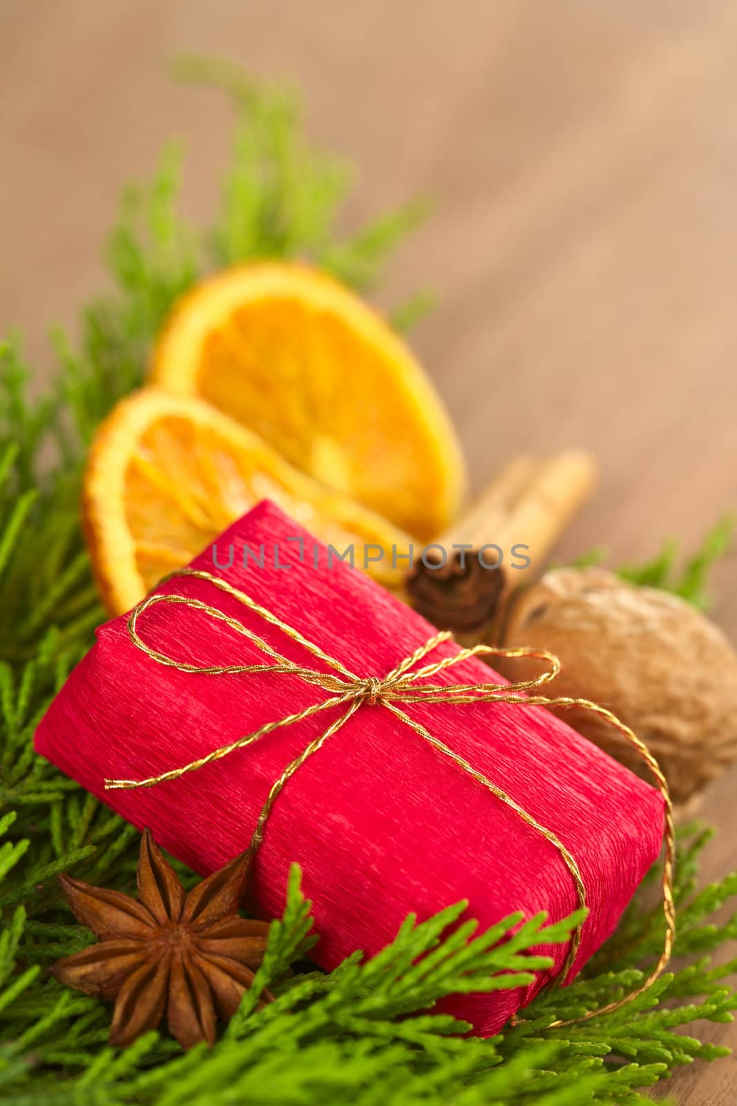 Christmas present on evergreen branch with anise, dried orange slices, cinnamon and walnut (Selective Focus, Focus on the middle of the present)