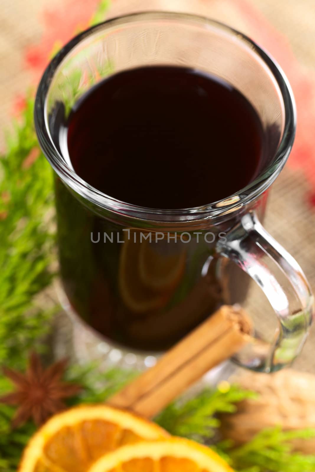 Hot mulled wine with spices and evergreen (Selective Focus, Focus on the front rim of the glass)