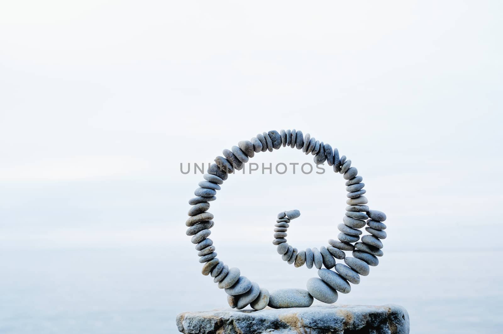 White spiral of pebbles on the boulder at the sea